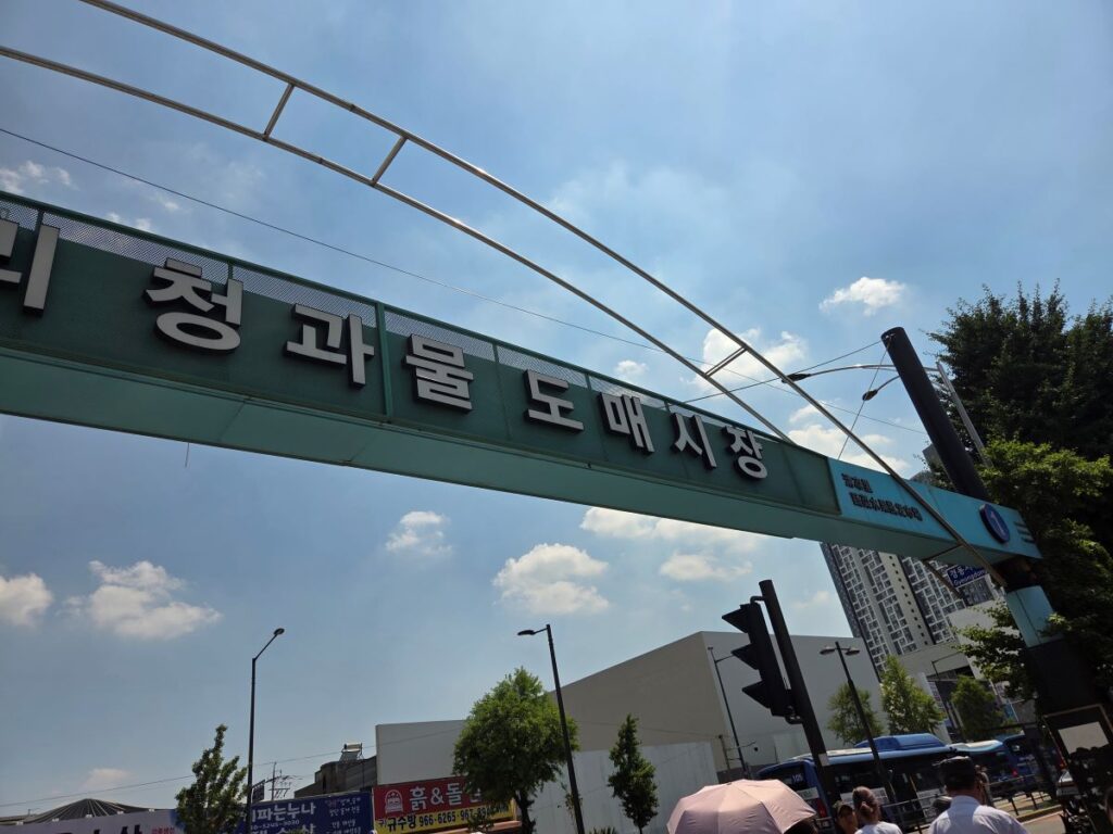청량리 청과물 도매시장 1번 게이트 주변에서 차량과 방문객이 함께 보이는 시장 입구 풍경